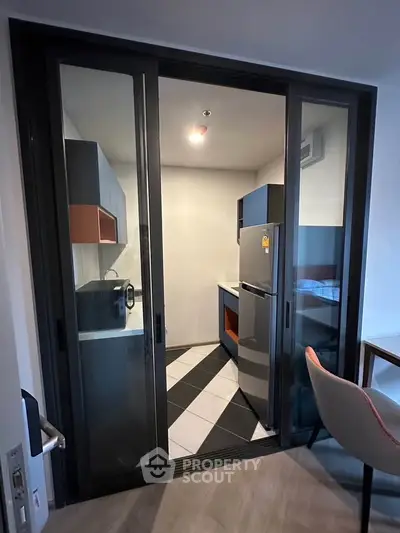 Modern compact kitchen with sliding glass doors and sleek appliances in a stylish apartment.