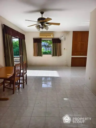 Spacious living room with ceiling fan and large windows offering natural light