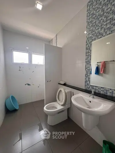 Modern bathroom with sleek fixtures and stylish tile accents, featuring a toilet and sink under natural light.