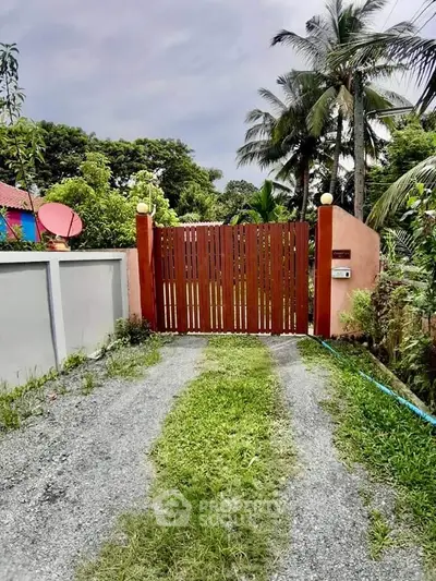 Charming gated entrance with lush greenery and tropical palm trees, perfect for a serene retreat.