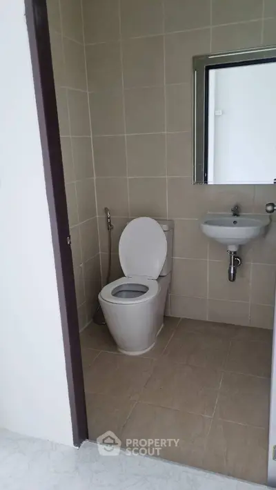 Compact bathroom with modern fixtures and neutral tile design.