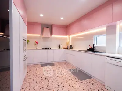 Modern kitchen with pink cabinets and terrazzo flooring, featuring sleek appliances and ample counter space.