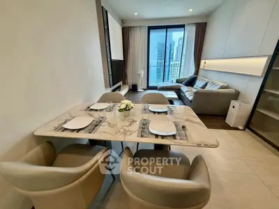 Modern living room with dining area and city view, featuring elegant furniture and stylish decor.