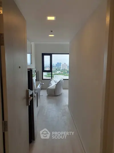Modern apartment hallway leading to a cozy living area with city view.