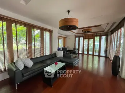 Spacious living room with modern decor and large windows offering garden views.