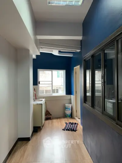 Spacious interior with blue accent wall and large windows, perfect for natural light.