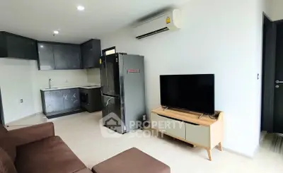 Modern open-layout living room with kitchen, featuring sleek appliances and contemporary furniture.