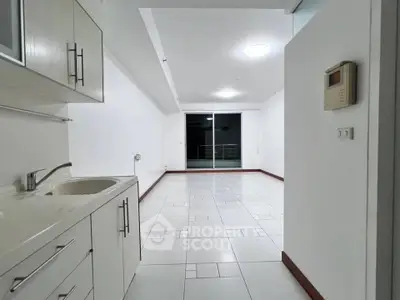 Spacious open-plan kitchen and living area with modern white cabinetry and tiled flooring.