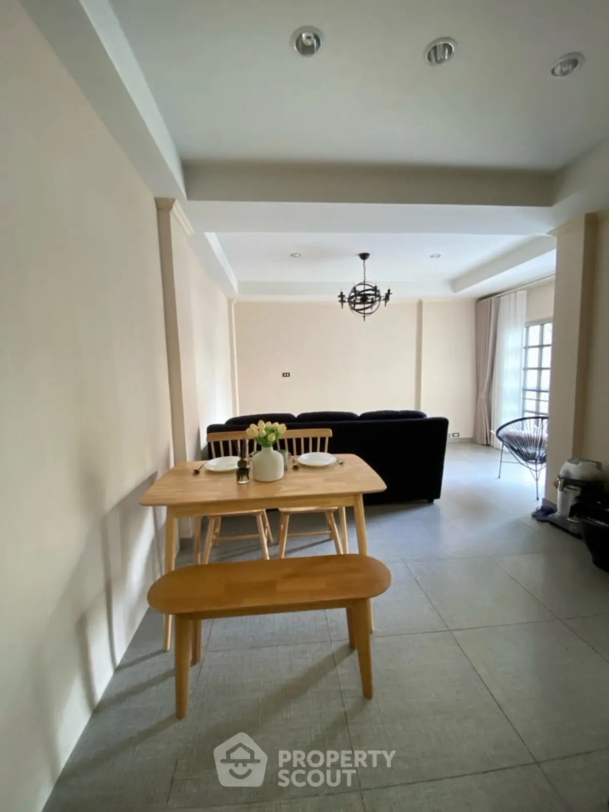 Spacious living room with modern dining area and stylish lighting in a cozy apartment.