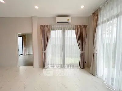 Spacious living room with large windows and elegant curtains