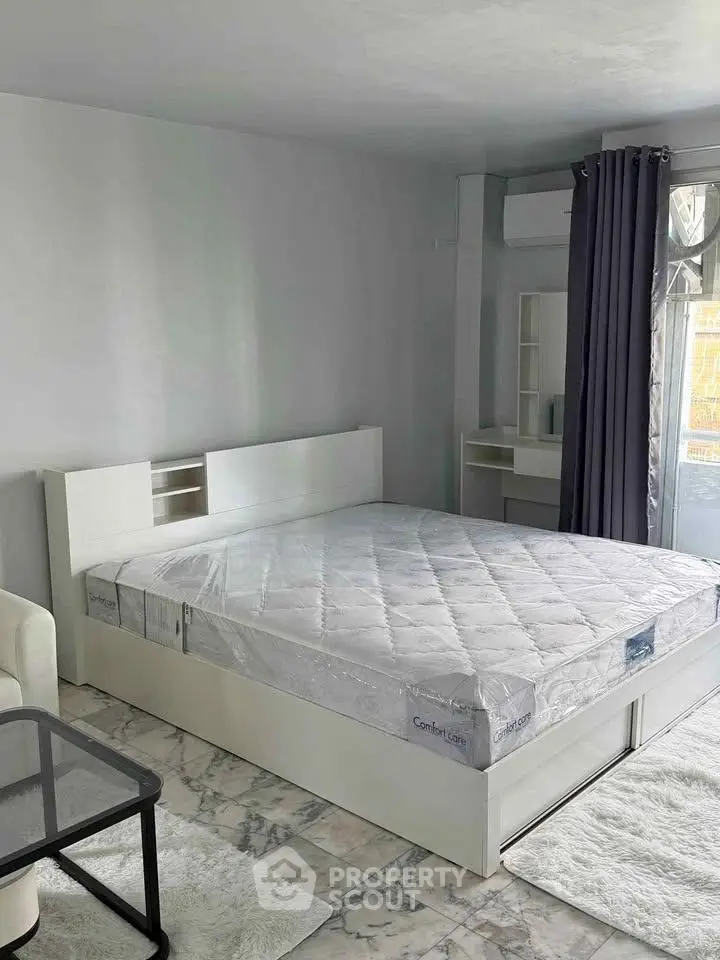 Spacious bedroom with modern decor and large window for natural light