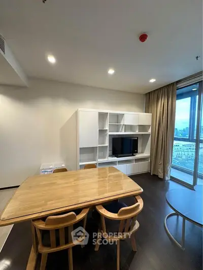 Modern dining area with wooden table and chairs, built-in TV unit, and city view balcony.