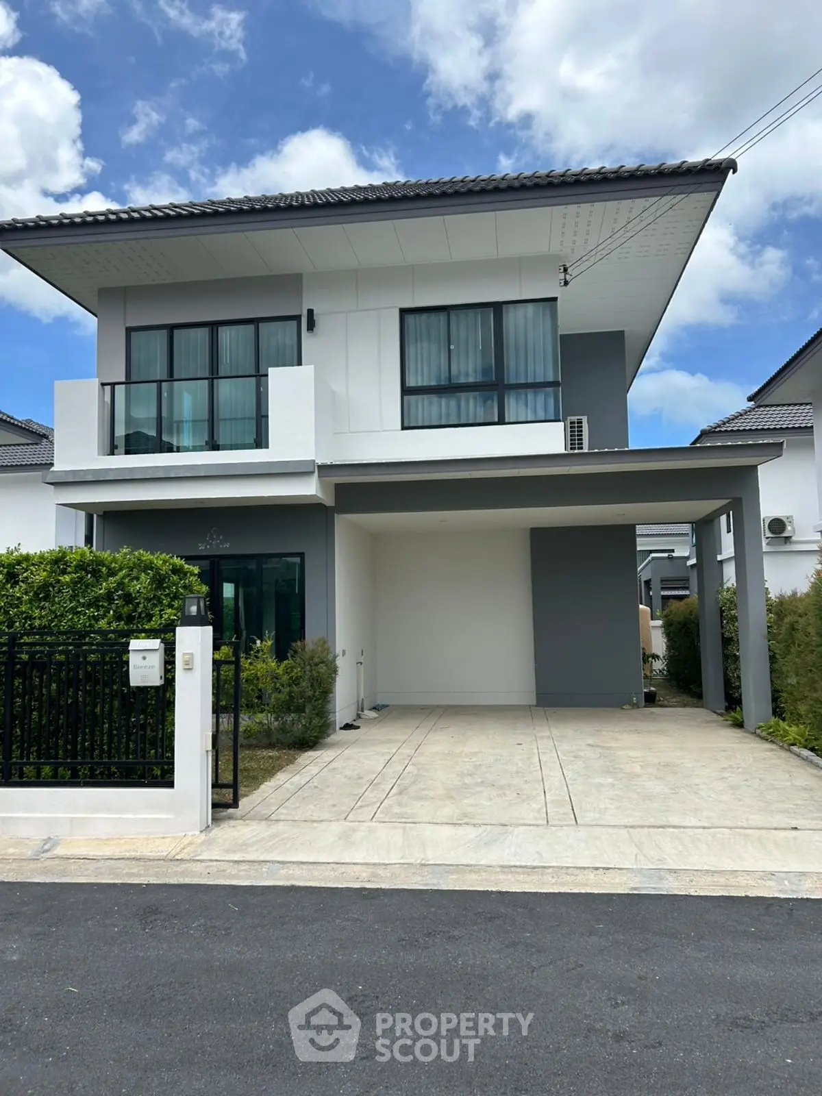Modern two-story house with driveway and lush greenery