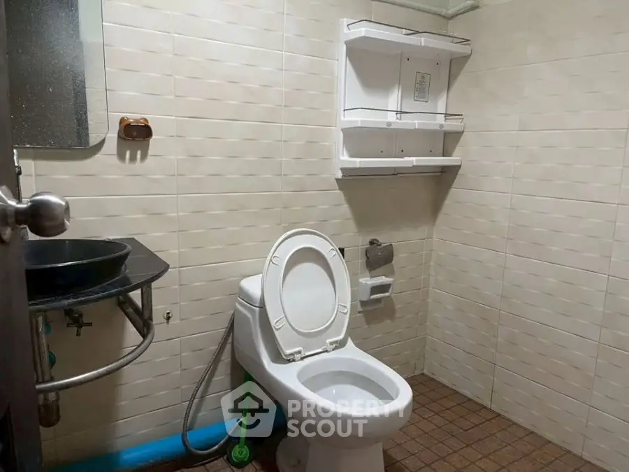 Functional bathroom with modern fixtures and tiled walls, featuring a toilet and sink.