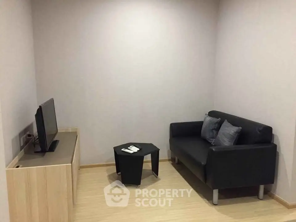 Cozy minimalist living room with modern black sofa and flat-screen TV.
