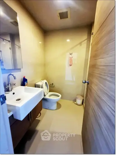 Modern bathroom with sleek fixtures and neutral tones, featuring a spacious sink and toilet.