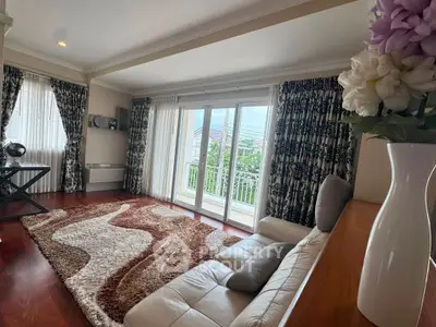 Elegant living room with large windows and stylish decor, featuring a cozy sofa and plush rug.