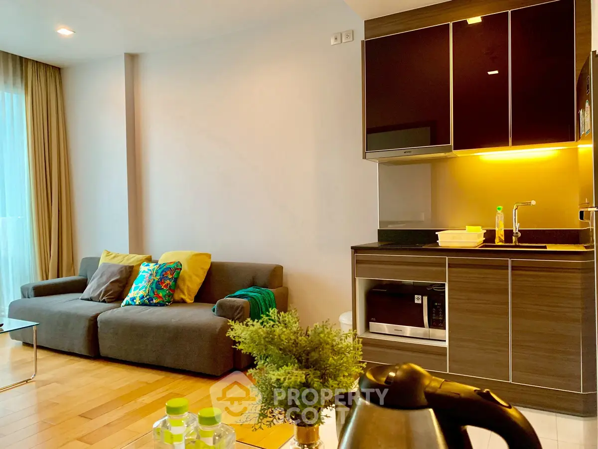 Modern living room with kitchenette, featuring cozy sofa and stylish decor.