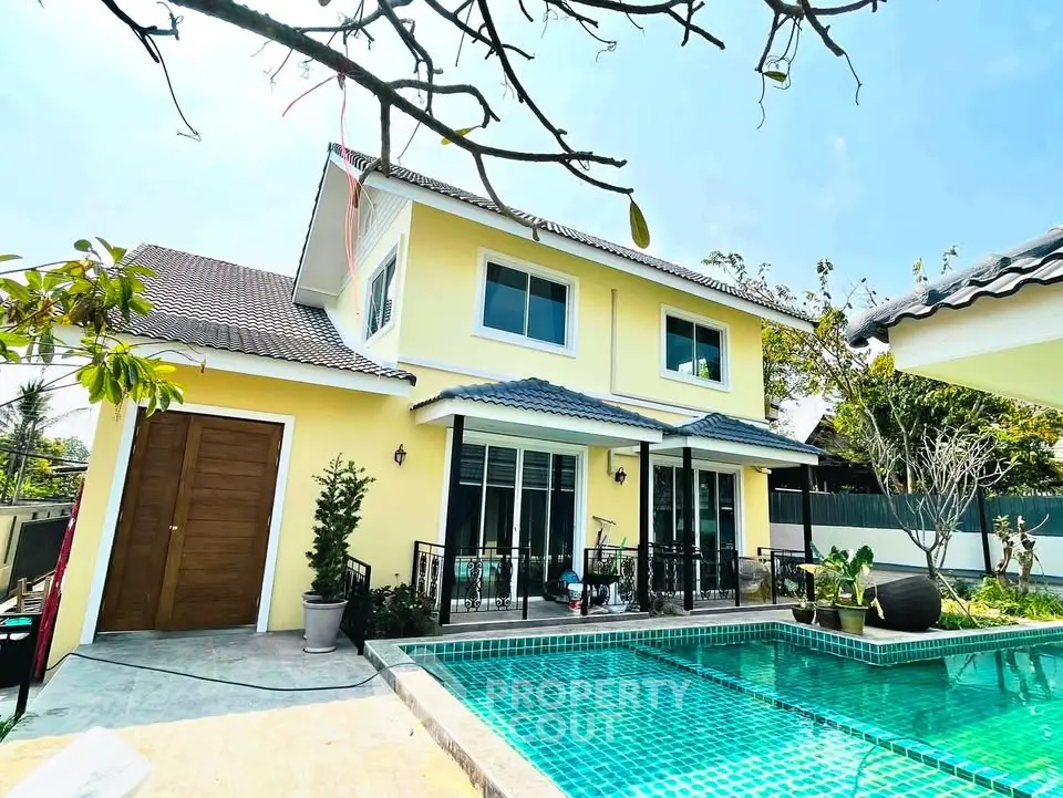 Stunning two-story yellow house with private pool and lush garden, perfect for luxurious living.