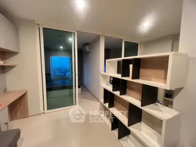 Modern apartment interior with stylish shelving and sliding glass doors leading to a balcony with city view.
