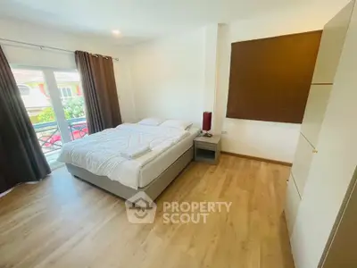 Spacious bedroom with large window and modern decor, perfect for relaxation.