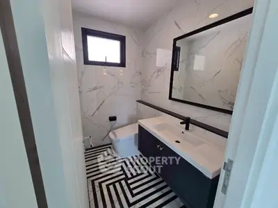 Modern bathroom with stylish black and white geometric flooring and marble walls.