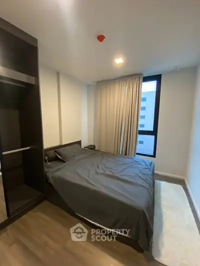 Modern bedroom with large window and sleek design in urban apartment.