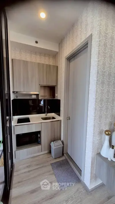 Modern compact kitchen with sleek cabinetry and built-in appliances in a stylish apartment.