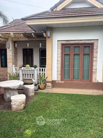 Charming suburban home with lush green lawn and cozy outdoor seating area, perfect for relaxation.