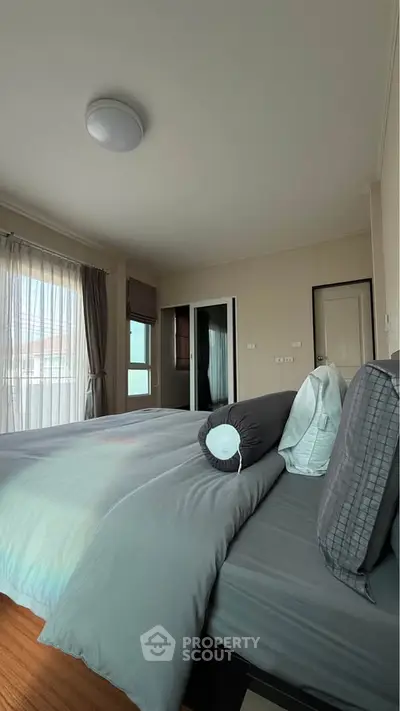 Spacious bedroom with large windows and modern decor, offering ample natural light and a cozy atmosphere.