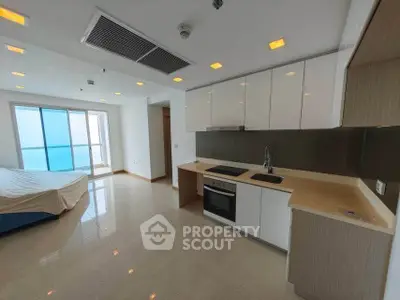 Modern open-layout kitchen with sleek cabinetry and built-in oven in a bright apartment.