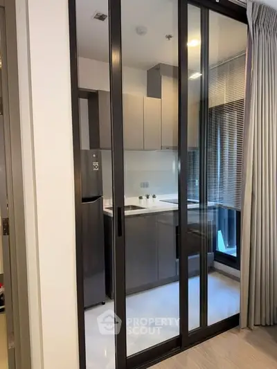 Modern kitchen with sleek design and glass sliding doors in a contemporary apartment.