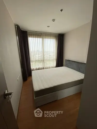 Cozy bedroom with large window and modern furnishings in a stylish apartment.