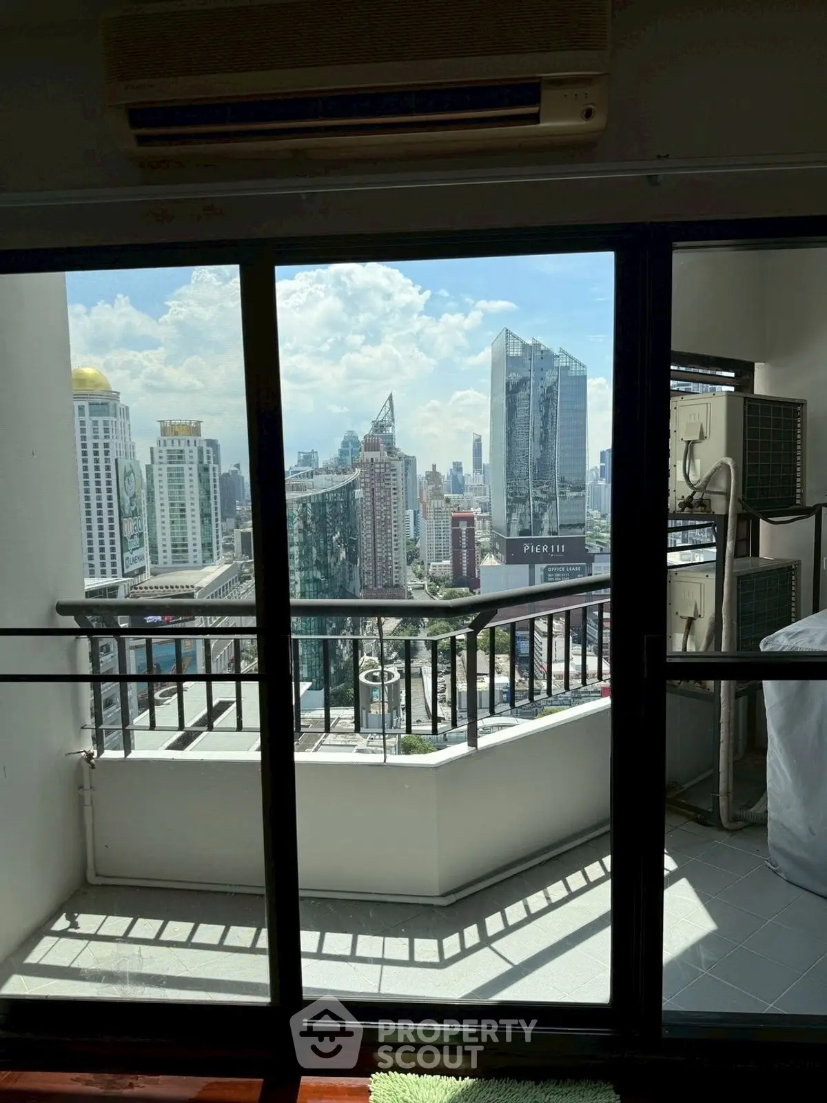 Stunning city view from modern balcony with glass doors in high-rise apartment.