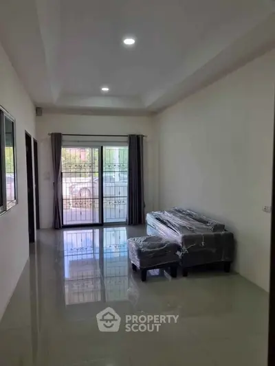 Spacious living room with large windows and modern furniture, perfect for natural light and comfort.