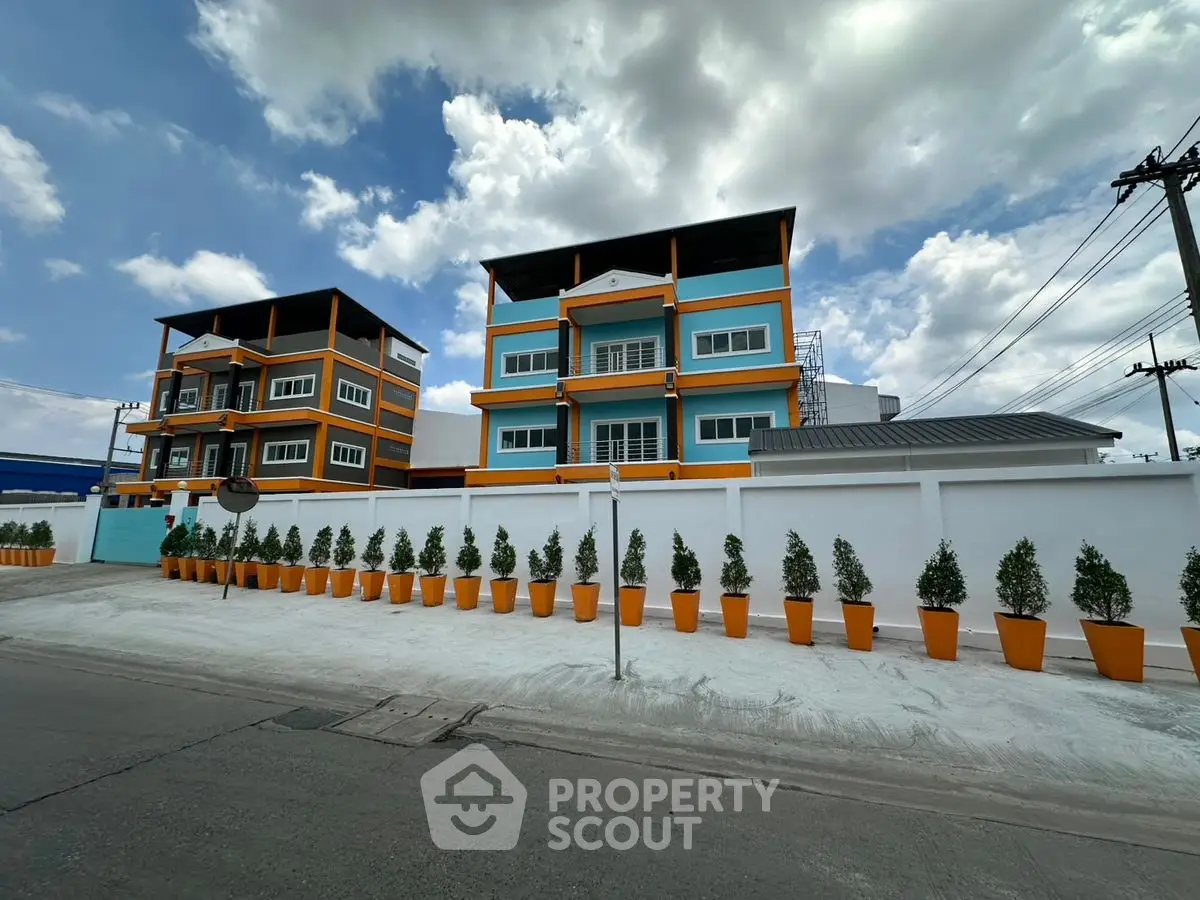 Modern apartment building with vibrant colors and potted plants lining the entrance.