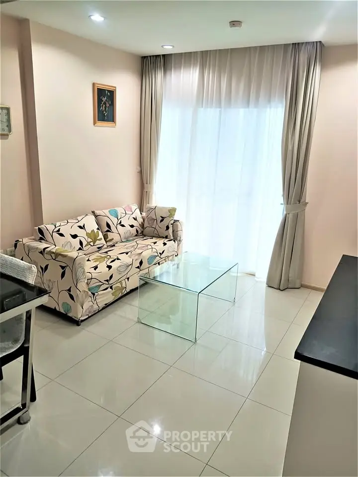 Bright living room with floral sofa and glass coffee table, perfect for modern living.
