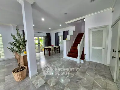 Spacious open-plan living area with elegant staircase and natural light.
