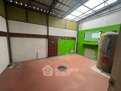 Spacious tiled area with partial roof, ideal for storage or utility use.