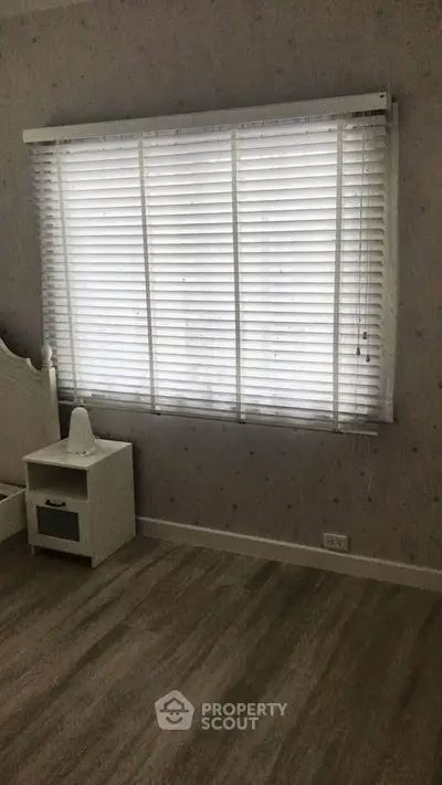 Cozy bedroom with large window and wooden flooring, perfect for natural light lovers.