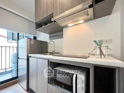 Modern kitchen with sleek cabinetry, microwave, and balcony access in a stylish apartment.