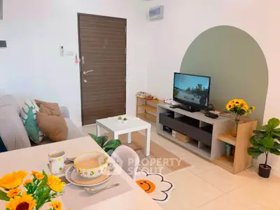 Charming living room with modern decor and cozy ambiance, featuring a stylish TV setup and vibrant plants.