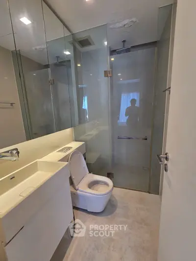 Modern bathroom with glass shower and sleek fixtures in a contemporary apartment.