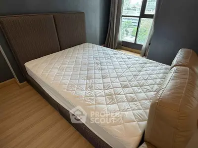 Spacious bedroom with large window and modern bed in a stylish apartment.