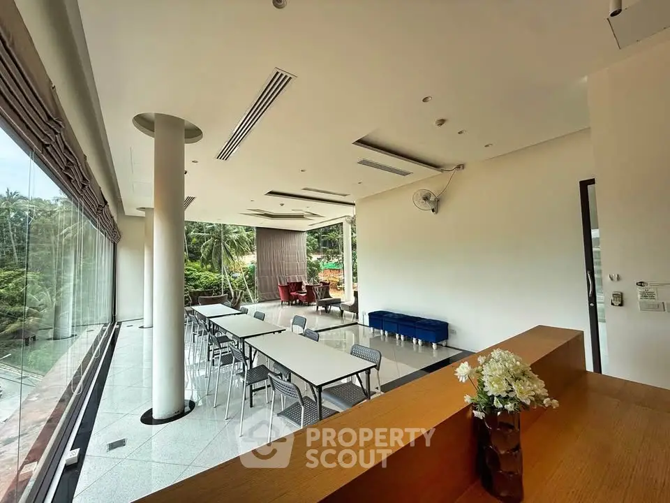 Spacious modern living area with large windows and lush garden view, perfect for relaxation and gatherings.