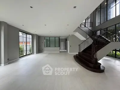 Spacious modern living room with elegant staircase and large windows