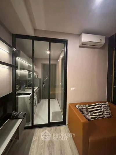 Modern living room with glass partition and air conditioning, featuring sleek design and cozy seating.