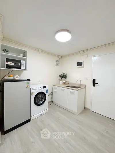 Modern compact kitchen with washing machine and microwave, ideal for small apartments.