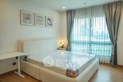 Spacious bedroom with large window and modern decor in a city apartment.