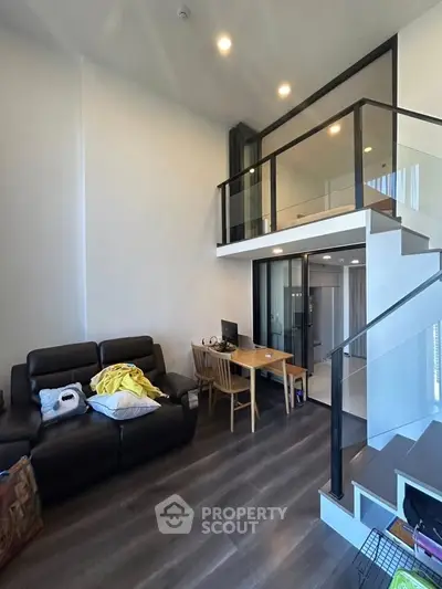 Modern loft-style living room with high ceiling and mezzanine, featuring sleek furniture and elegant design.